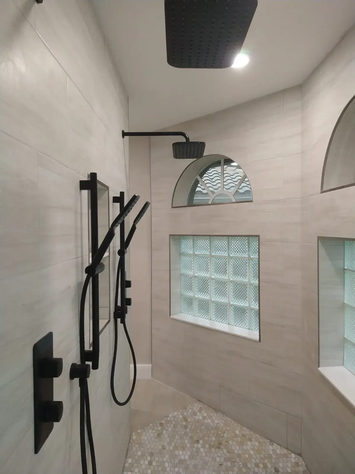 Walk-in shower with matte black rainfall and handheld fixtures