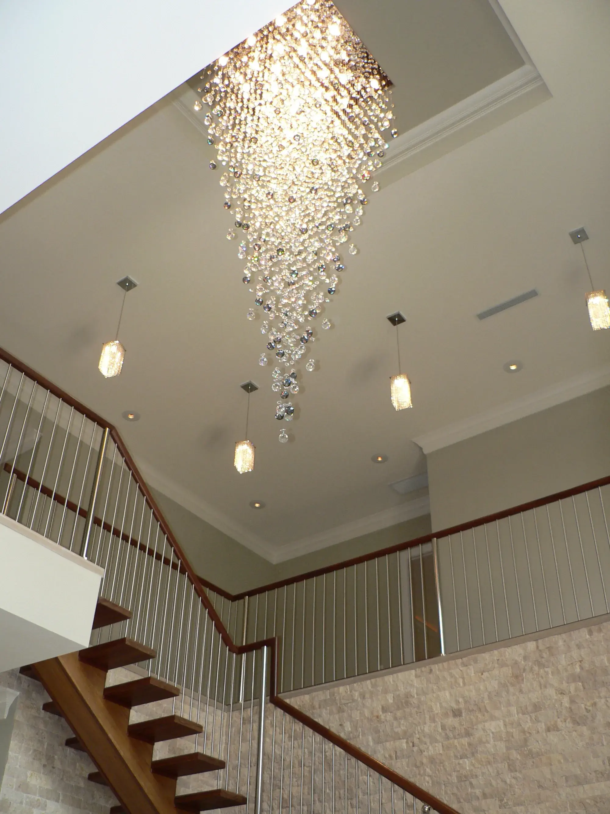 Renovated foyer with sweeping staircase and cascading chandelier