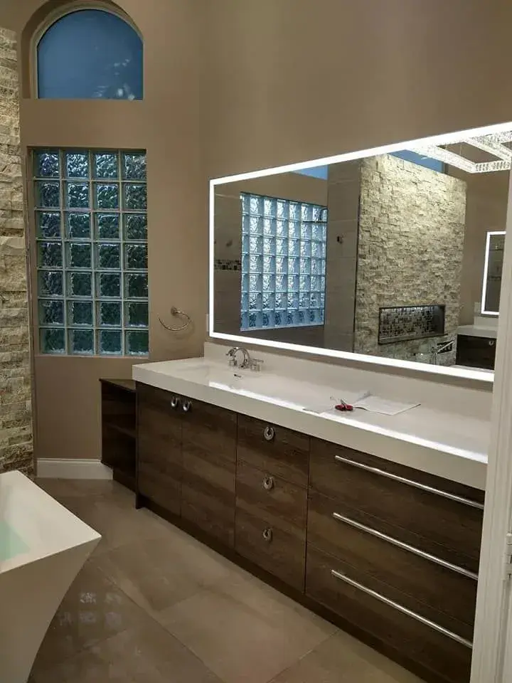 Floating vanity with backlit mirror against a stone feature wall